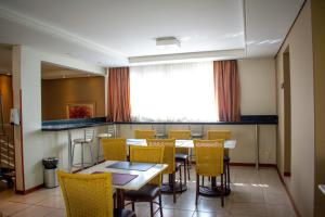 a dining room with a table and yellow chairs at Barigui Park Hotel in Curitiba