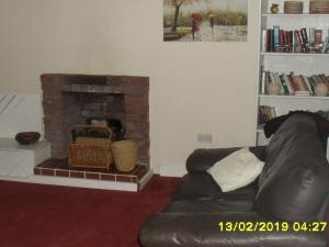 a living room with a couch and a brick fireplace at The Old Library & Lodge in Arisaig