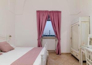 um quarto com uma cama e uma janela com cortinas vermelhas em Casal Duca em Taranto