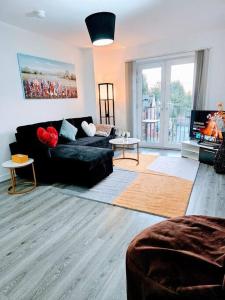 a living room with a black couch and a tv at Swanky 1-Bedroom Apt in Walsall in Bescot