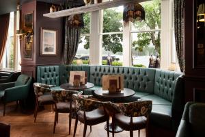 a restaurant with two tables and a green couch at The Waterhead Inn, Ambleside- The Inn Collection Group in Ambleside
