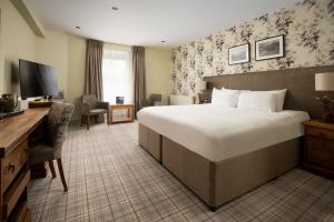 アンブルサイドにあるThe Waterhead Inn- The Inn Collection Groupの大きなベッドとデスクが備わるホテルルームです。