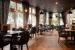 um restaurante com mesas, cadeiras e janelas em The Waterhead Inn- The Inn Collection Group em Ambleside