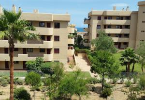 an apartment building with palm trees in front of it at Apartment in La Cala de Mijas in La Cala de Mijas