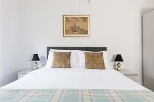 a bedroom with a white bed with two lamps at 4 Canon Lane in Chichester