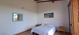 a white bedroom with a bed and a window at Finca Buena Vista in Guatapé
