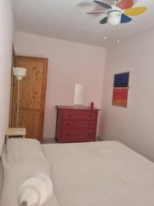 um quarto com uma cama, uma ventoinha de tecto e uma cómoda em Casa vista mare golfo di Budoni em Budoni
