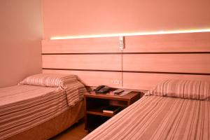 a hotel room with two beds and a phone on a table at Barigui Park Hotel in Curitiba