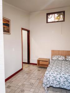 a bedroom with a bed and a table and a window at Pousada Estância Mineira in Guapé