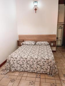 a bedroom with a bed and a cross on the wall at Pousada Estância Mineira in Guapé