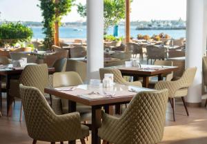 - un restaurant avec des tables et des chaises offrant une vue sur l'eau dans l'établissement Cleopatra Luxury Resort Makadi Bay (Adults Only), à Hurghada