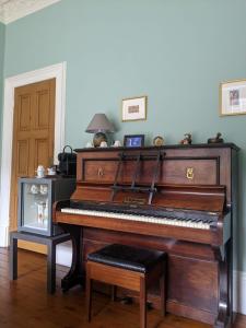a piano sitting in a living room with a table at McCrae's Bed and Breakfast in Edinburgh