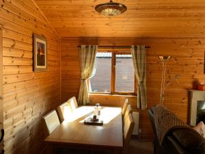 ein hölzernes Esszimmer mit einem Tisch und einem Fenster in der Unterkunft Immaculate 3-Bed Lodge in Hawick in Hawick