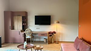 een woonkamer met een bureau en een tv aan de muur bij Sol'm Lodges in Solesmes