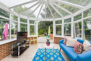 a conservatory with a blue couch and a glass ceiling at Sycamores - Fabulous family home with huge garden in Kent