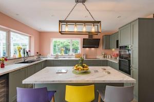 una cocina con una mesa con un bol de fruta. en Sycamores - Fabulous family home with huge garden en Kent