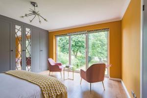 1 dormitorio con paredes de color naranja, 1 cama y sillas en Sycamores - Fabulous family home with huge garden en Kent