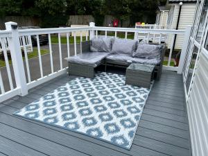 un patio con sofá y una alfombra en la terraza en Kayes Retreat Three bed caravan Newquay Bay Resort Quieter area of park, en Newquay