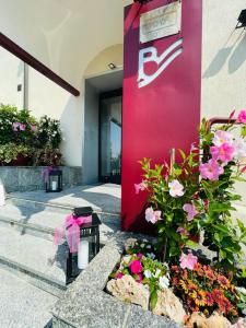 Hotel Bel Sit في Comerio: جدار وردي مع الزهور أمام المبنى