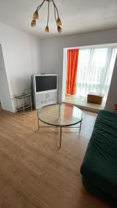 a living room with a glass table and a tv at Eden Apartament in Reghin