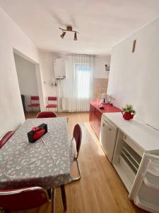 a room with a table and a kitchen with red chairs at Eden Apartament in Reghin