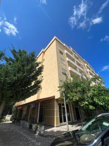 un edificio alto con una macchina parcheggiata di fronte di Pretty Home Kaonet a Orikum