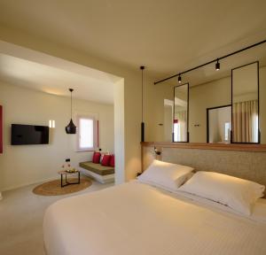 een slaapkamer met een groot wit bed en een spiegel bij 11:11 By Potnia in Akrotiri