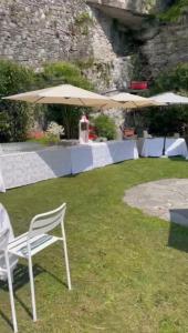 Hotel Bel Sit في Comerio: كرسي أبيض جالس في العشب مع مظلات