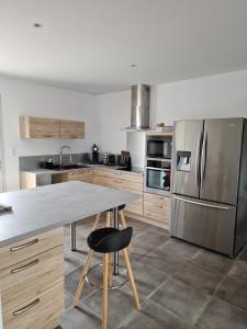a kitchen with a table and a stainless steel refrigerator at Cœur de village commerces proximité Center Parcs in Les-Trois-Moutiers