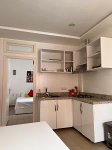 une cuisine avec des placards blancs et une chambre avec un lit dans l'établissement Well being point, à Agadir