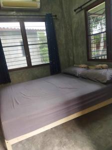 uma cama num quarto com duas janelas em BaanNakanoHomestay em Mae Rim