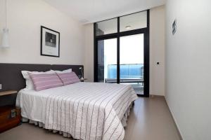 um quarto com uma cama com almofadas cor-de-rosa e uma janela em Luxury apartment Residencial Sunset Drive - Benidorm, España em Benidorm