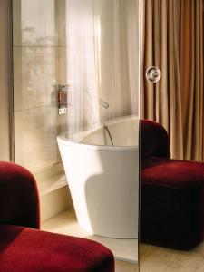 una vasca da bagno in una stanza con due sedie di Hotel Josef a Praga