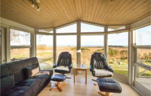 een woonkamer met een bank, stoelen en ramen bij Amazing Home In rsted With Kitchen in Ørsted