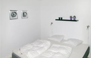 - un lit avec des draps blancs et 2 photos sur le mur dans l'établissement 4 Bedroom Stunning Home In Sindal, à Tolne