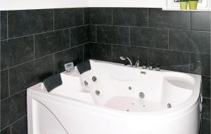 y baño con bañera blanca y azulejos negros. en 4 Bedroom Stunning Home In Sindal, en Tolne
