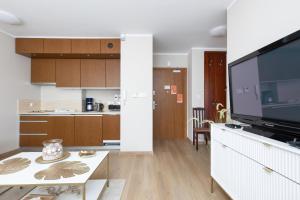 a living room with a large television and a kitchen at Apartamenty przy Promenadzie Villa Mistral II by Renters in Świnoujście