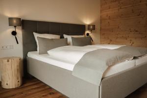 ein großes Bett in einem Schlafzimmer mit einer Holzwand in der Unterkunft Landhaus Engel in Erlaheim