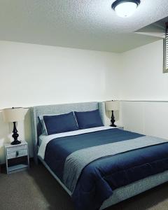 a bedroom with a blue bed with two lamps at Cochrane’s Finest Airbnb in Cochrane