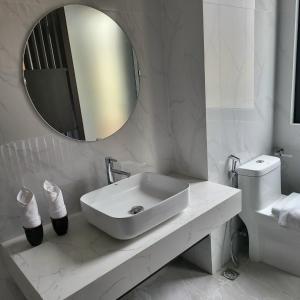 a white bathroom with a sink and a mirror at Miyabi Wyndham Thanh Thuỷ in Phú Thọ