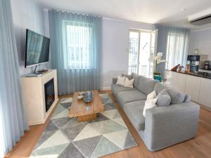 a living room with a gray couch and a television at FIRST Sellin - Appt 22 "Baltic Sea" mit seitlichem Meerblick in Ostseebad Sellin