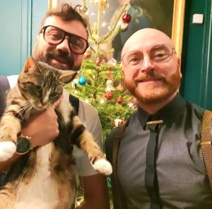 Un uomo che tiene un gatto davanti a un albero di Natale di Hotel Du Cygne Tours a Tours