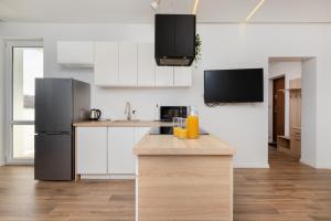a kitchen with white cabinets and a stainless steel refrigerator at Apartment Park de Gaulle Gdansk Wrzeszcz by Renters in Gdańsk