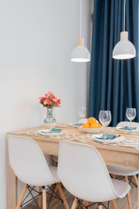 a dining room table with white chairs and a table with wine glasses at Apartment Park de Gaulle Gdansk Wrzeszcz by Renters in Gdańsk