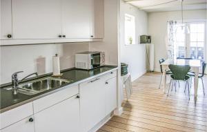 BagenkopにあるAmazing Apartment In Bagenkop With 2 Bedrooms, Sauna And Wifiのキッチン(白いキャビネット、テーブル、椅子付)