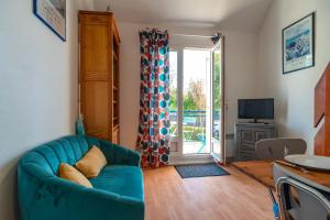 Glazik - Appartement à 5 min de la plage في Saint-Nic: غرفة معيشة مع أريكة زرقاء وباب زجاجي منزلق