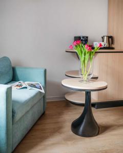 una mesa con un jarrón de flores junto a un sofá en Hotel H12****, en Cracovia