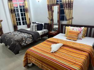 a bedroom with two beds and two windows at Embrace "The Fine Stay" in Nuwara Eliya