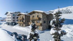 uma casa na neve com carros à frente dela em HERBERT - Boutique Apartments inkl Lungau Card em Katschberghöhe