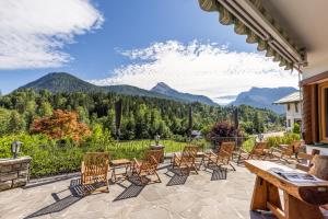 een patio met stoelen en een tafel met uitzicht op de bergen bij Haus Bergwelten in Bischofswiesen